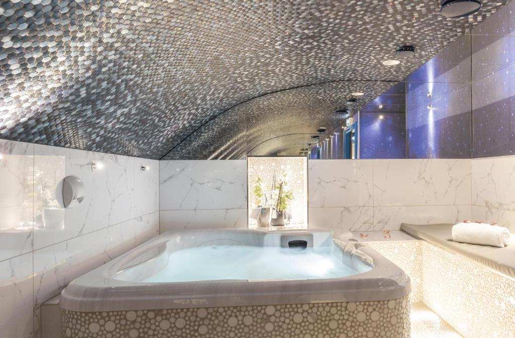 a bath tub in a bathroom with a ceiling at Secret de Paris - Hotel & Spa in Paris