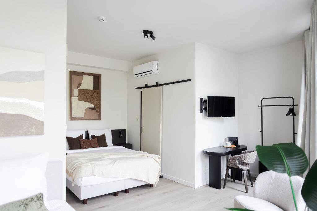 a white bedroom with a bed and a chair at ROMY ANTWERP Sint-Jansvliet in Antwerp