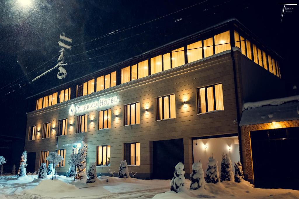 a large building with lights on in the snow at Palermo Hotel in Vanadzor
