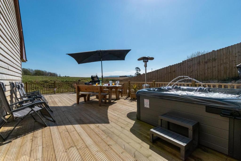 a hot tub on a deck with a table and an umbrella at 3 Bed in Coelbren oc-way238 in Coelbren