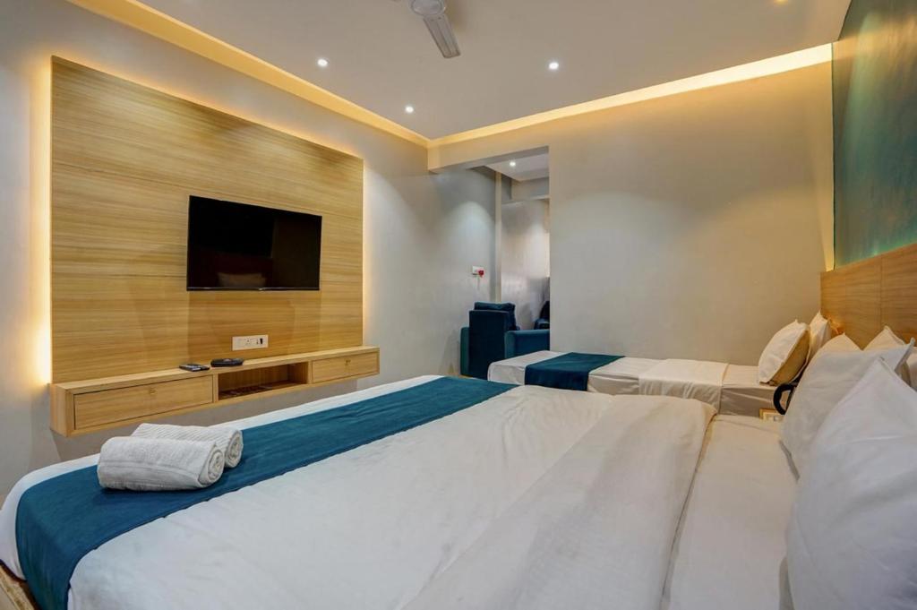 a bedroom with two beds and a flat screen tv at Hotel H One in Pune