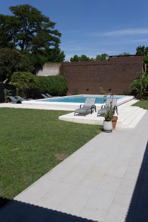 a swimming pool with two benches in a yard at Primer Peldaño - Casa Quinta in Junín