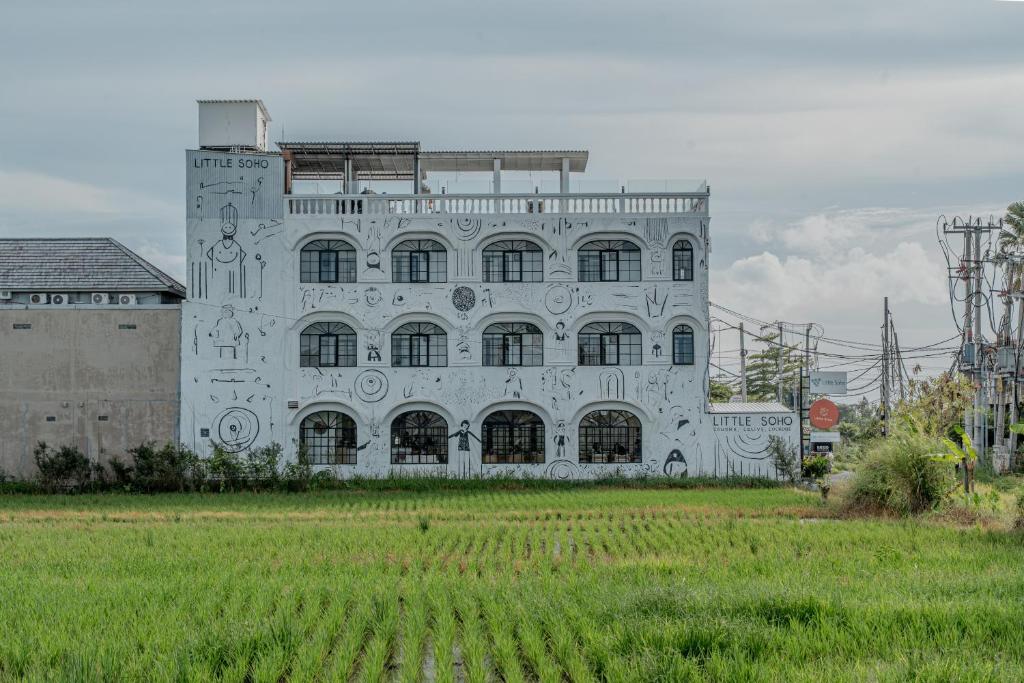 a large white building with a field in front of it at Little Soho Pererenan in Canggu