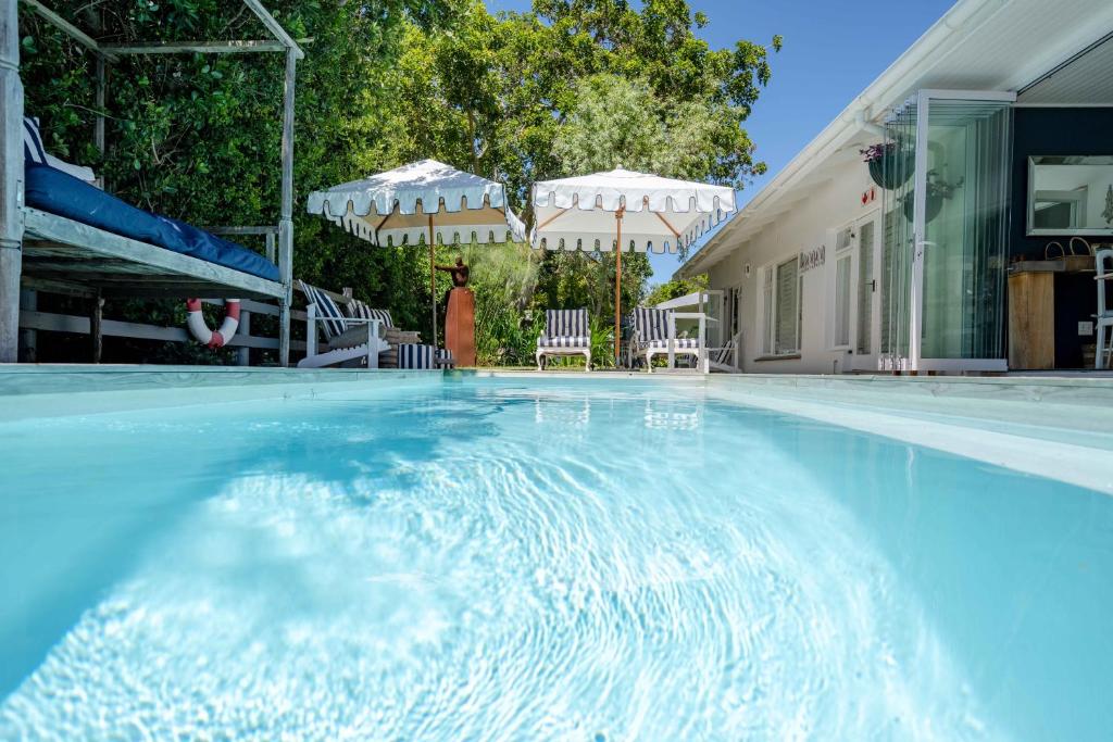 a swimming pool with two umbrellas and a pool at Long Story Guest House in Plettenberg Bay