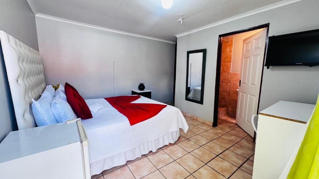a bedroom with a bed with red and blue pillows at Village Boiketlo in Bloemfontein