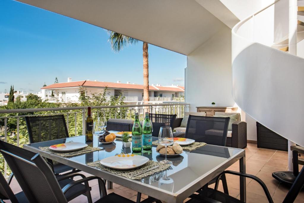 a table with food and wine on a balcony at Casa Louro in Cabanas de Tavira