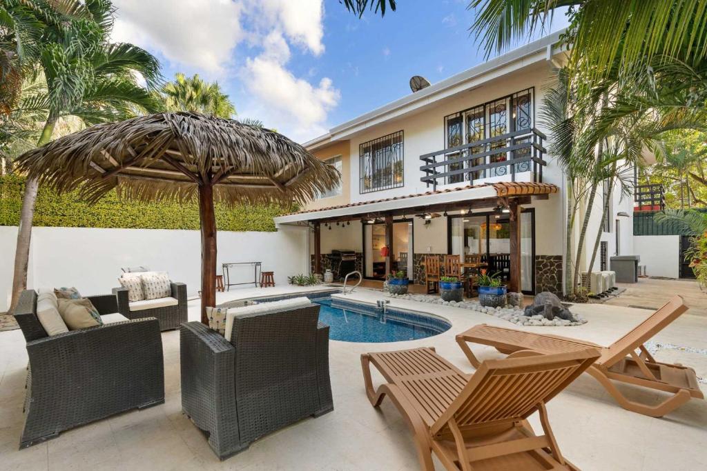 a house with a swimming pool with chairs and an umbrella at Spacious Home with Private Pool & Covered Patio Near the Beach in Playa Flamingo