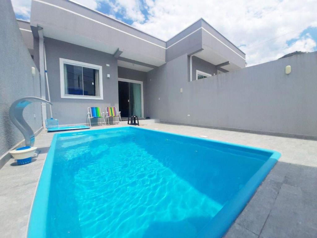 a large blue swimming pool in front of a house at Pool house próximo ao centro in Matinhos