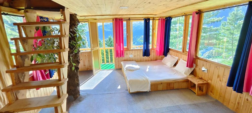 a small room with a bed and some windows at Jibhi Pine Nature Tree house in Jibhi