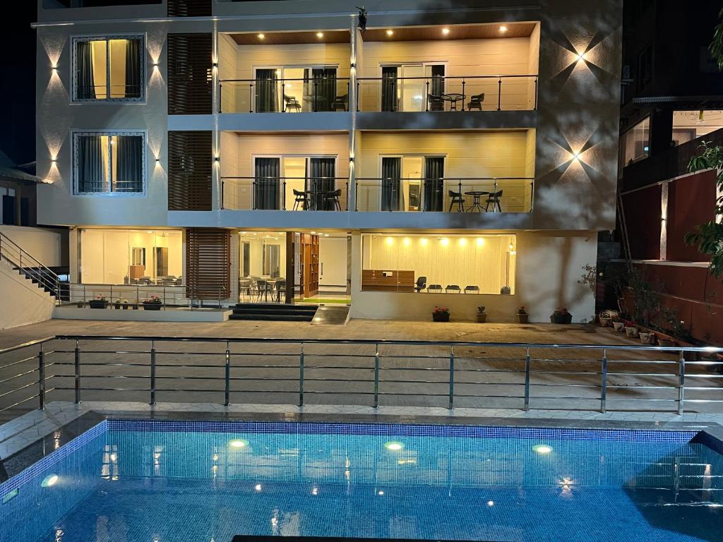 a house with a swimming pool in front of a building at Gugal Bliss in Mahabaleshwar