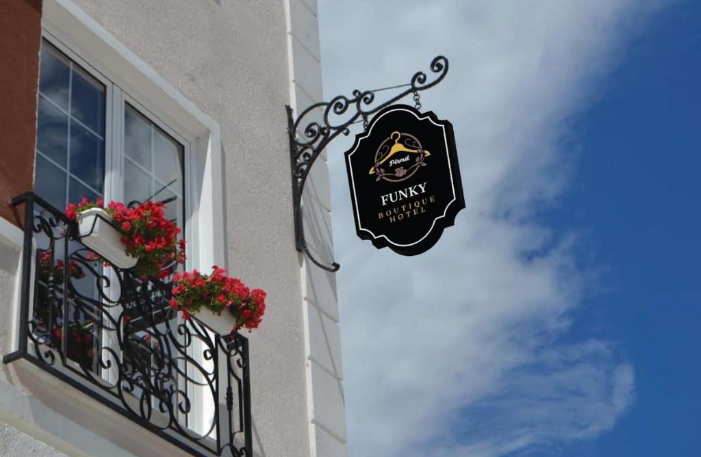 a sign on the side of a building with flowers on a balcony at Funky Boutique Hotel & Adventures in Përmet