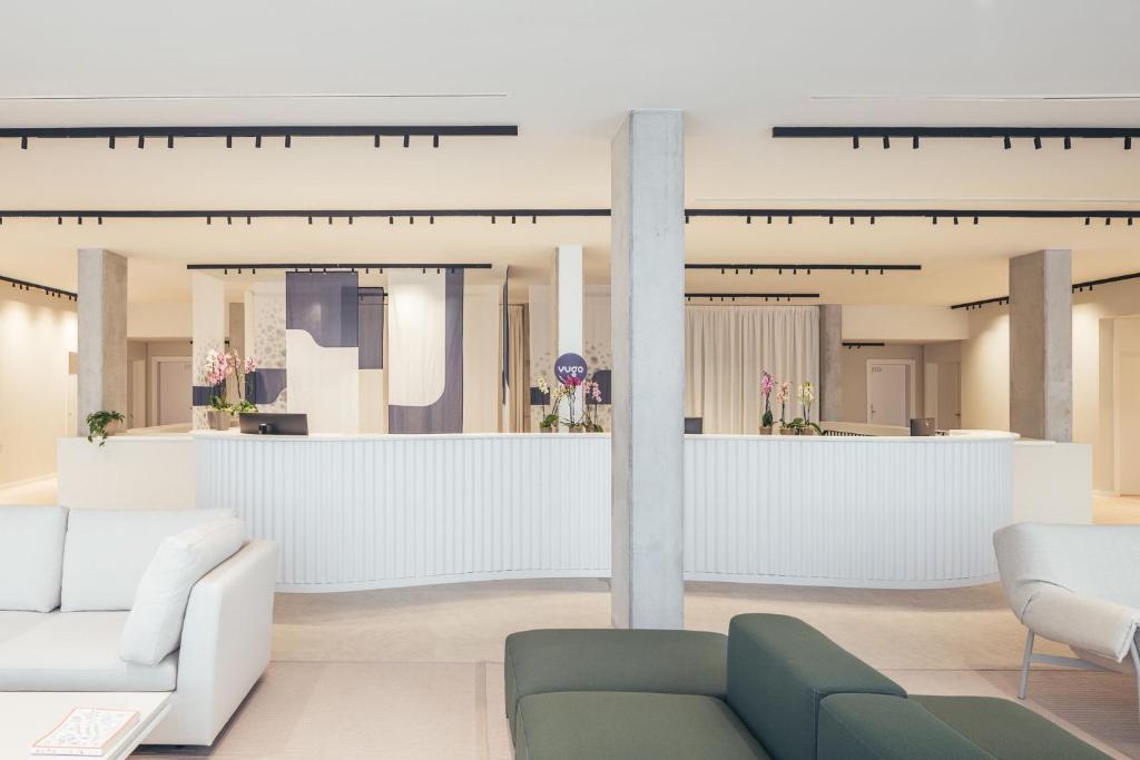 a lobby with white furniture and a reception counter at Yugo Terrassa Can Telar in Terrassa