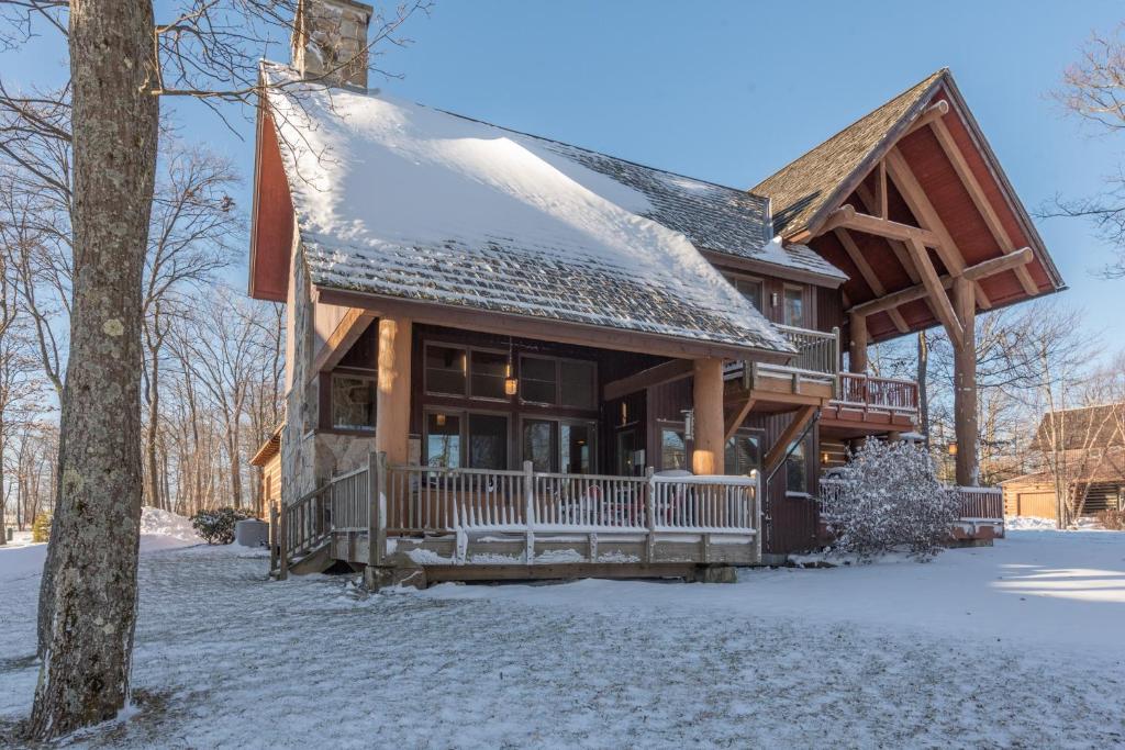 a log cabin in the winter with snow on the ground at WISPer by Railey Vacations in McHenry