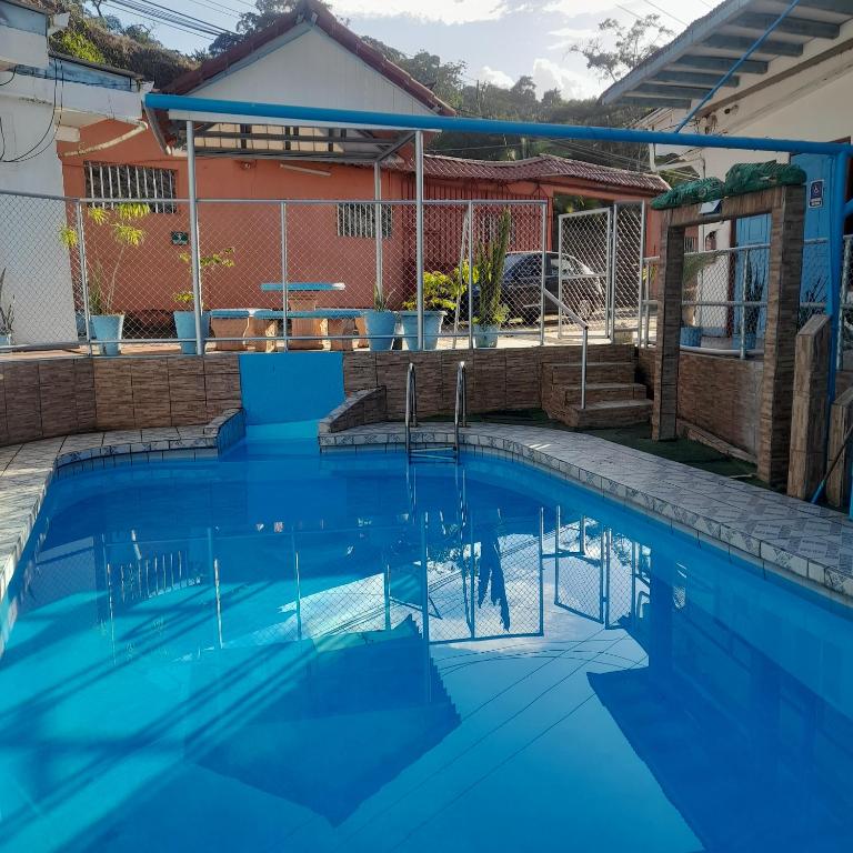 a swimming pool with blue water in front of a house at Hotel La Uvita in Puerto Limón