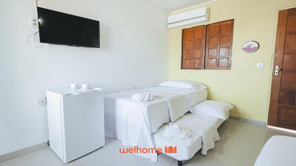 a room with four white towels and a tv at Suite em Guriri Norte com Piscina e Academia in São Mateus