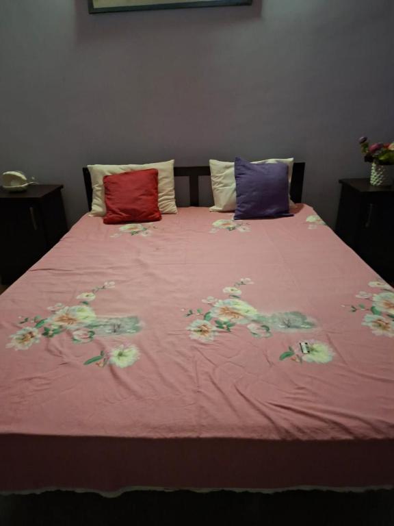 a bed with pink sheets with flowers on it at ADLi in Belihuloya