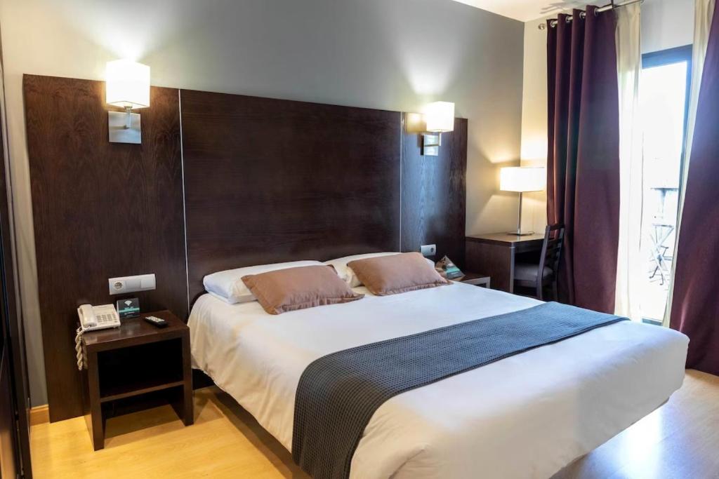 a bedroom with a large bed with a wooden headboard at Hotel Cardeña by gaiarooms in Burgos