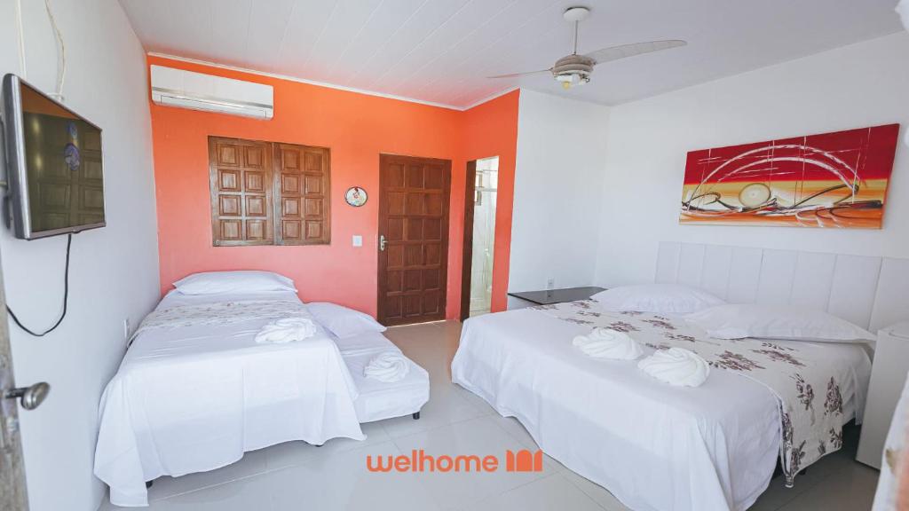 two beds in a room with an orange wall at Suite em Guriri Norte com Piscina e Conforto in São Mateus