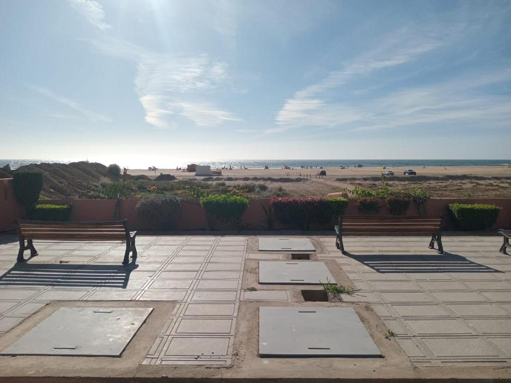 two benches sitting on a patio looking at the beach at Appartement pieds dans l'eau Aghroud in Tamri