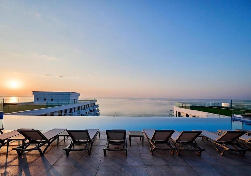 a pool on the roof of a building with chairs at Waves 342 Infinity in Mamaia Sat/Năvodari