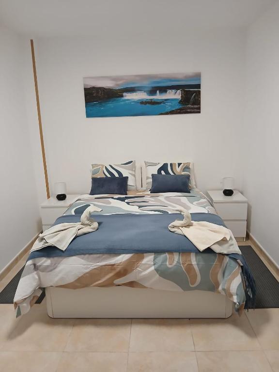 a bedroom with a bed with a painting on the wall at ATICO ACOGEDOR LA LAGUNa in Las Lagunas