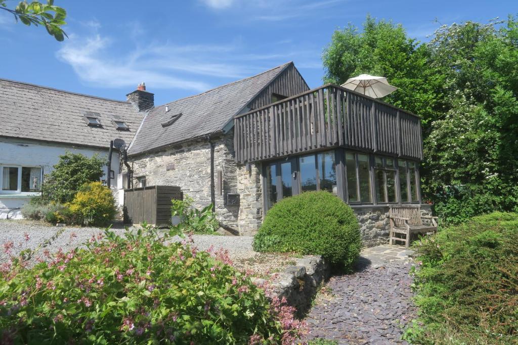 ein altes Steinhaus mit einer Terrasse an der Vorderseite in der Unterkunft Welsh Hideaways in Pentre-briwnant