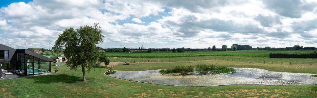 an aerial view of a field with a pond in the middle at Oase 41 - 5 STAR location with Indoor swimming pool & unique landscape view in Sint-Laureins