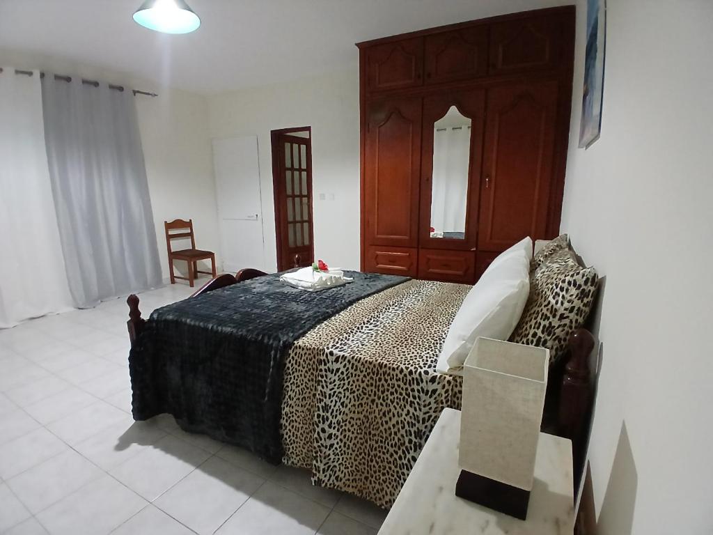 a bedroom with a bed with a wooden headboard and a chair at ROMANA guest house in Tarrafal da Vila de Ribeira Grande