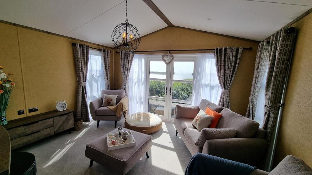a living room with couches and chairs and a large window at 1 Sunset View in Millom