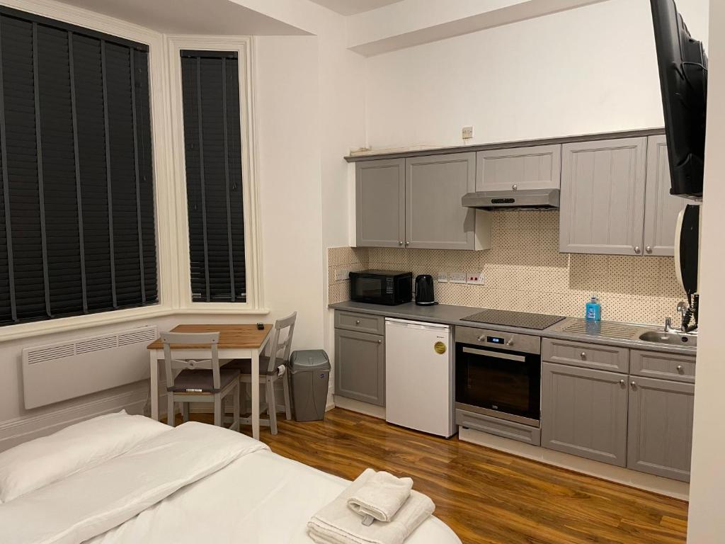 a kitchen with white cabinets and a bed in a room at Self Contained Studio Flat Acton Central West London in London