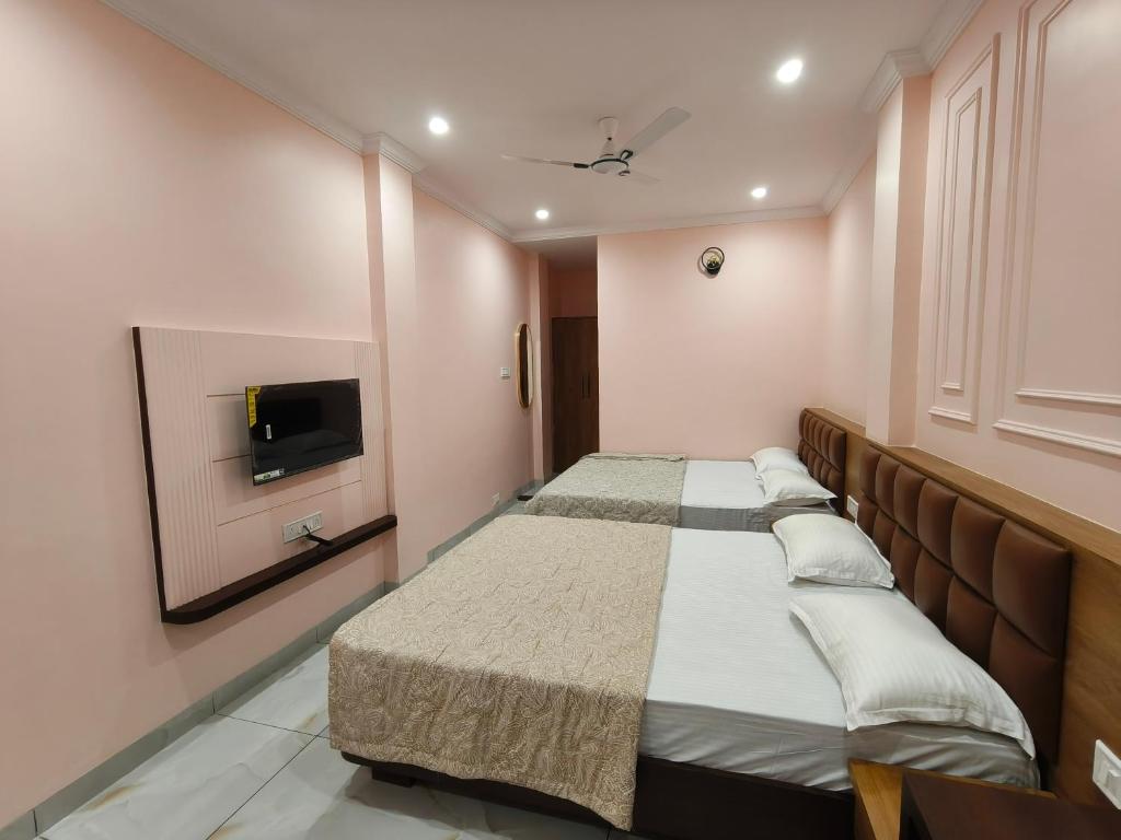 two beds in a room with a tv on the wall at Hotel Kanak Shree in Godarpura