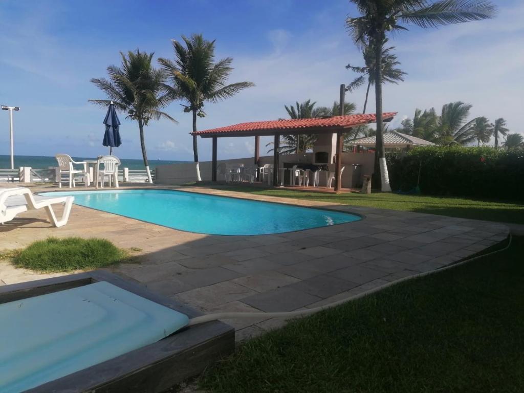 a swimming pool with a gazebo and the ocean at Pousada Tropical dos Corais in Cabo de Santo Agostinho