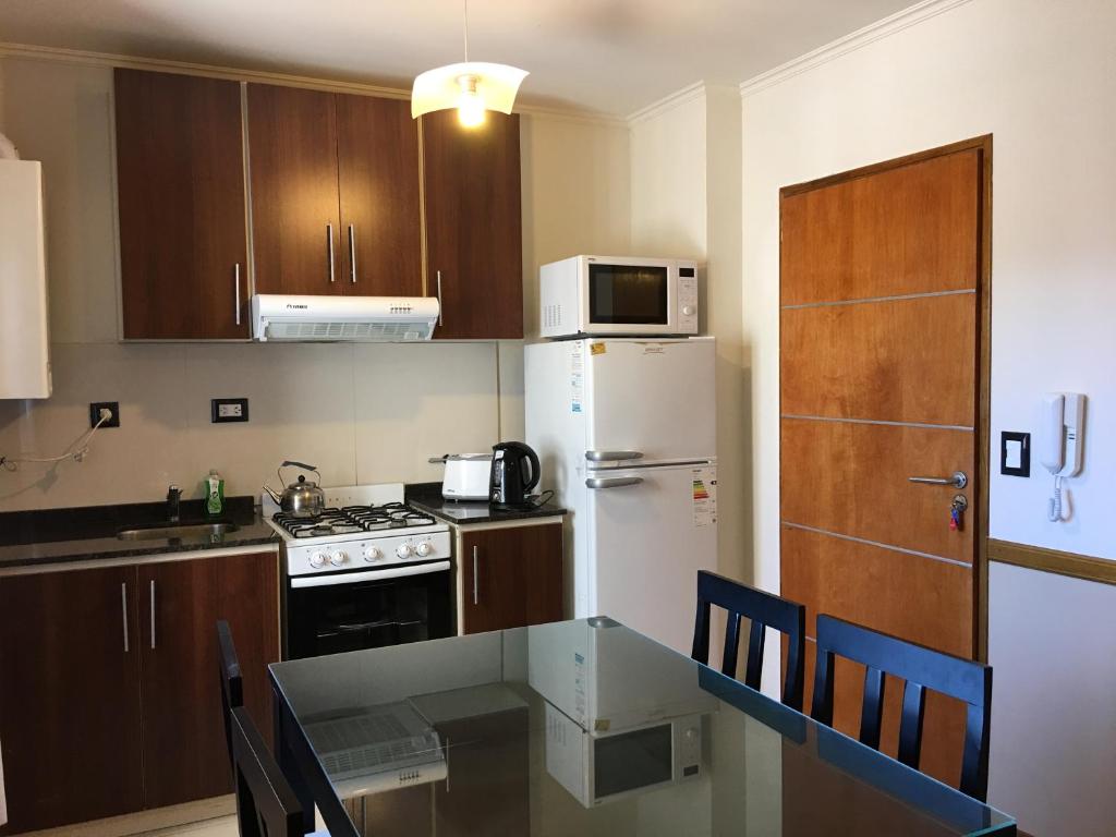 a kitchen with a table and a white refrigerator at Aires de la Villa in Villa Carlos Paz