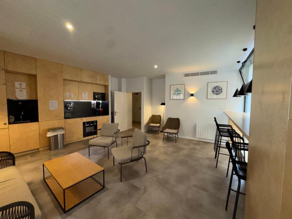 a living room with chairs and tables and a kitchen at Urban Cube Hostel Granada in Granada