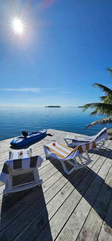 a dock with two chairs and a boat on the water at Raiatea Sunrise villa in Taputapuapea