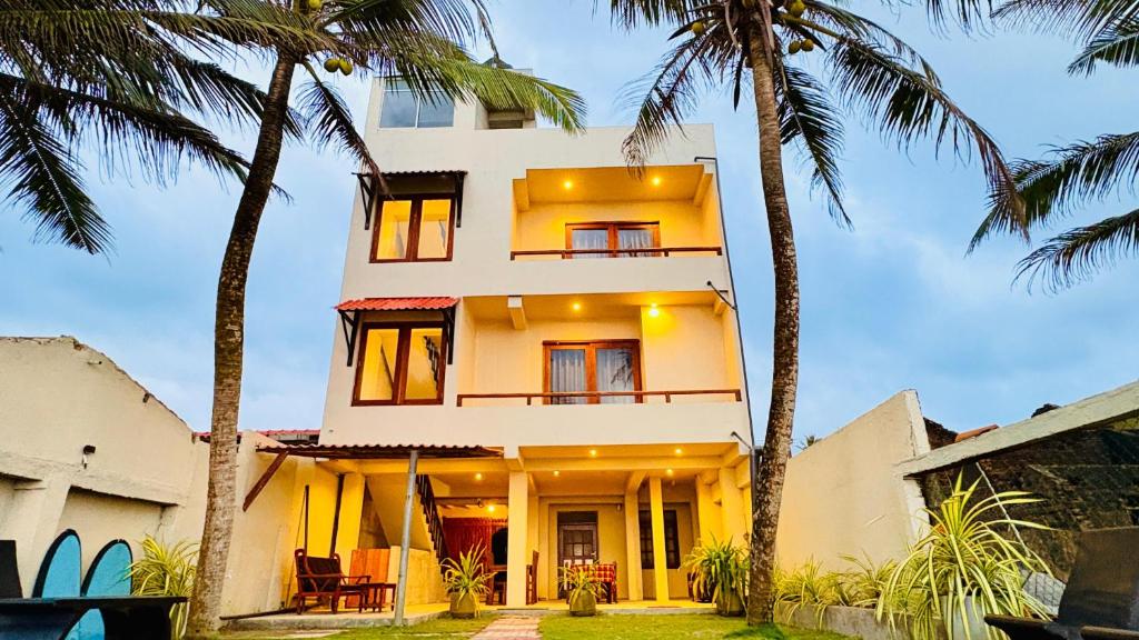 a building with palm trees in front of it at Ayomal Beach Paradise in Galle