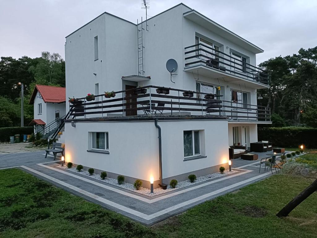 a white building with a balcony on top of it at Noclegi Piaskowa 44 in Nowa Karczma