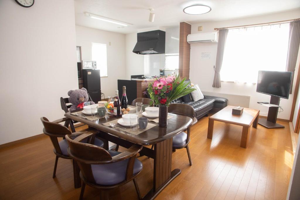 a living room with a table and a couch at Guest House Nishimiyanosawa in Teine