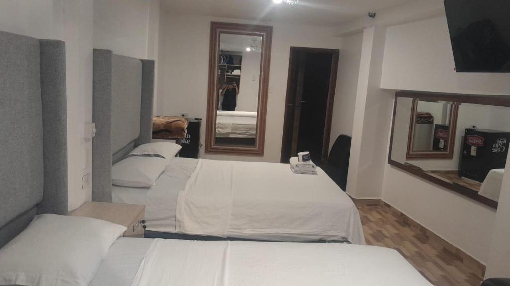 a room with four beds and a mirror at HotelesR20 in Lima