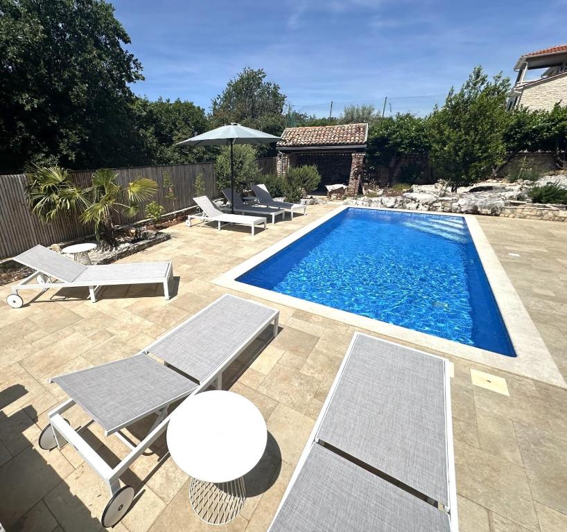 a swimming pool with chairs and an umbrella at Villa Doba - Visnjan in Višnjan