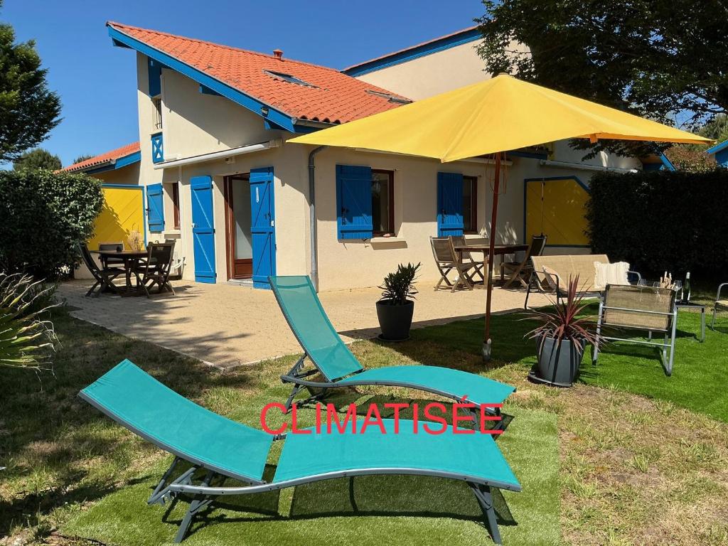a pair of chairs and an umbrella in front of a house at Ocelandes 39 in Saint-Julien-en-Born