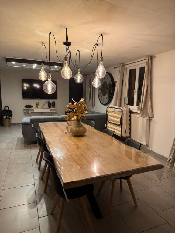 a dining room with a wooden table and lights at Maison à la campagne in Mecquignies