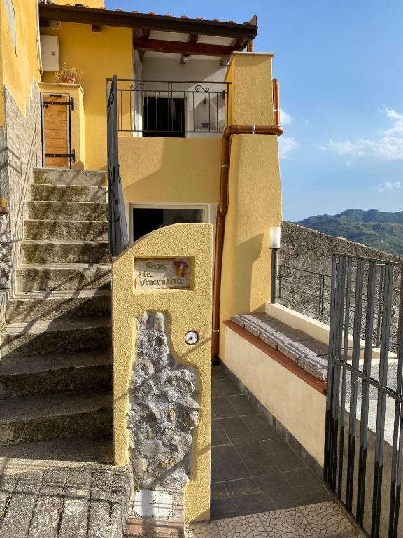 a yellow building with stairs and a balcony at Casa zia Vincenzina in Casalvecchio Siculo