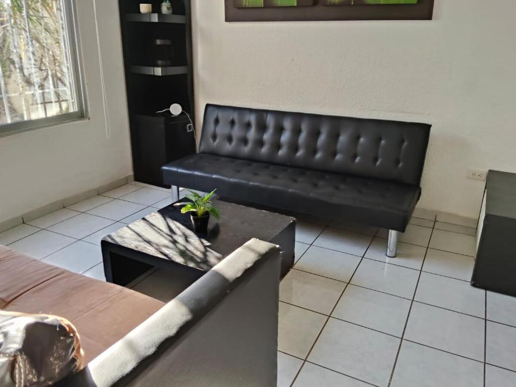 a black leather couch in a room with a table at Casa pame 2026 in Mérida