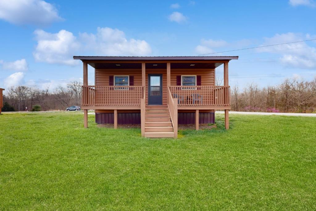 a log cabin with a deck on a grass field at Cabin 2: Lakeside in Murphysboro in Etherton