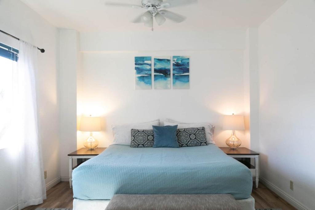 a bedroom with a blue bed with two lamps at North Shore Bungalow in Mokuleia
