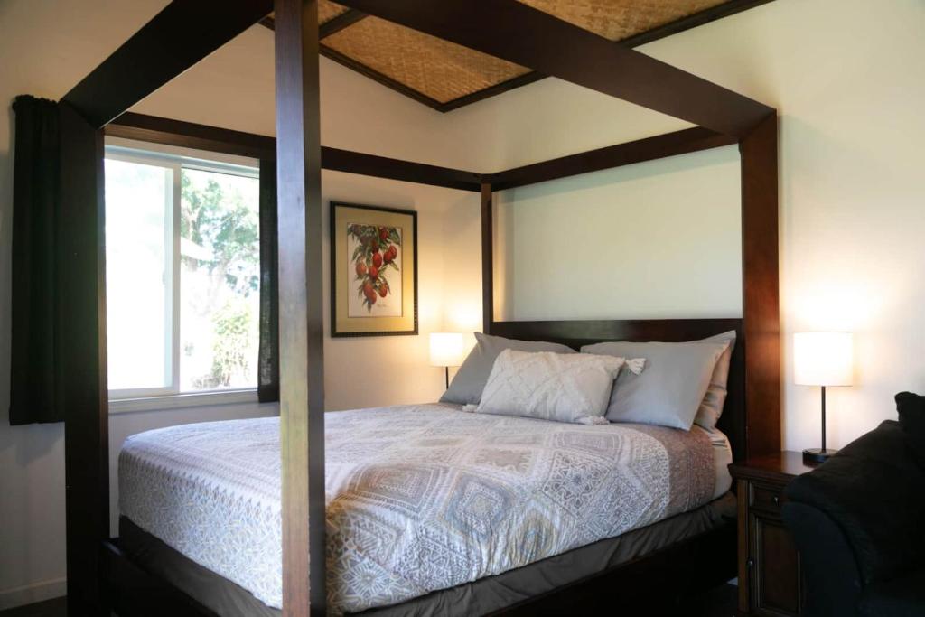 a bedroom with a canopy bed with a window at North Shore Studio in Mokuleia