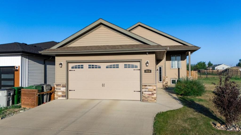 a house with a white garage door on a driveway at Spacious 4BR with King Suite - Garage - Netflix in Lloydminster