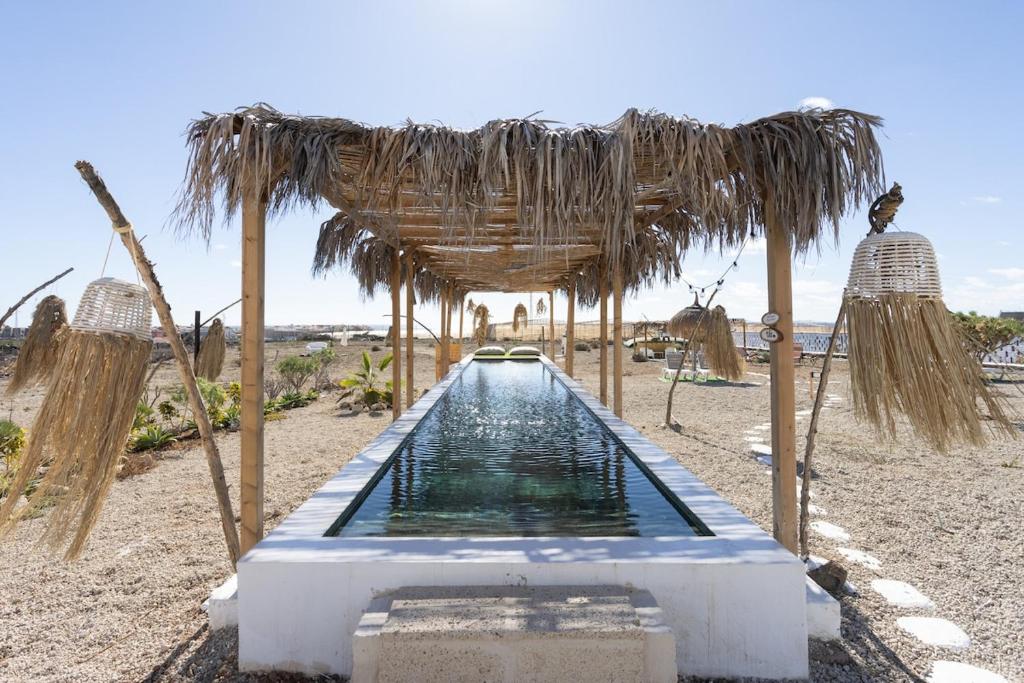 a pool of water under a straw umbrella on the beach at Eden Rentals Oasis Boho 1 in Las Galletas