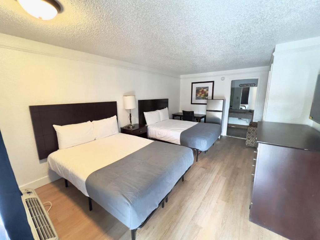 a hotel room with two beds and a desk at Airport Inn in Tulsa